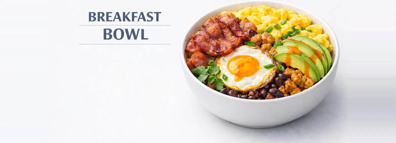 A breakfast bowl with scrambled eggs, bacon, a fried egg, sausage crumbles, black beans and sliced avocado, labeled Breakfast Bowl